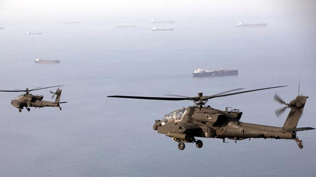 Helicopters flying over body of water with ships.